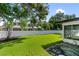 Lush backyard features a well-maintained lawn, mature trees, a white fence, and a glimpse of the house at 1881 Orchid St, Sarasota, FL 34239