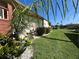 View of the home's backyard and landscaping, featuring a lush lawn and tropical plants at 19358 Edgewater Dr, Port Charlotte, FL 33948