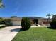 Charming single-story home featuring solar panels, a two-car garage, and a well-manicured lawn under a clear blue sky at 19358 Edgewater Dr, Port Charlotte, FL 33948