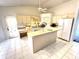 Bright kitchen featuring white appliances, tiled floors, a central island, and neutral cabinetry at 19358 Edgewater Dr, Port Charlotte, FL 33948