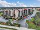Stunning exterior view of a condominium complex with a red roof, lush landscaping and ample parking at 21405 Olean Blvd # 224, Port Charlotte, FL 33952
