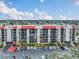Wide exterior shot of a condominium building with a red roof and parking lot on a sunny day at 21405 Olean Blvd # 224, Port Charlotte, FL 33952