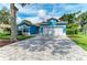 A spacious brick driveway leads to a charming blue home with a well-manicured lawn at 220 39Th Ne St, Bradenton, FL 34208