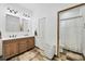 Bright bathroom featuring a wood vanity with double sinks and a white-tiled shower with a neutral color scheme at 39700 State Road 70 E, Myakka City, FL 34251