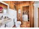Rustic bathroom showcasing wood paneling, a classic sink, and a neighboring laundry area with tile floors at 39700 State Road 70 E, Myakka City, FL 34251