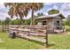 Exterior view of wooden structure featuring mature palms, fencing and drinking trough at 39700 State Road 70 E, Myakka City, FL 34251