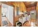 Rustic laundry area featuring wood walls and tile floors; includes a white utility sink and modern appliances at 39700 State Road 70 E, Myakka City, FL 34251