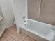 Clean bathroom featuring a soaking tub with white tile surround and a large window with horizontal blinds at 4354 Rock Creek Dr, Port Charlotte, FL 33948