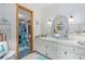 Well-lit bathroom featuring a vanity with storage, a decorative mirror, and a closet with organized shelving at 4888 Old Ranch Rd, Sarasota, FL 34241