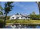 Charming home featuring a covered front porch overlooking a tranquil pond and lush green lawn at 4888 Old Ranch Rd, Sarasota, FL 34241