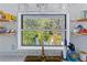Kitchen sink features open shelving with colorful dishware and window view of lush landscaping at 4888 Old Ranch Rd, Sarasota, FL 34241