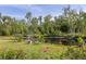 Lush garden with vibrant flowers and a tranquil pond featuring a fountain, surrounded by mature trees at 4888 Old Ranch Rd, Sarasota, FL 34241