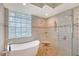 Spa bathroom featuring free standing tub, glass shower with pebble floor, and accent wall with glass block window at 5080 Timber Chase Way, Sarasota, FL 34238