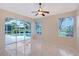 Living room with tile floors featuring a ceiling fan and sliding glass doors leading to a screened-in pool at 5080 Timber Chase Way, Sarasota, FL 34238