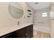 Modern bathroom with dark wood vanity, round mirror, floating shelves and updated shower at 5124 Palm Aire Dr, Sarasota, FL 34243