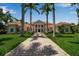 Beautifully landscaped home with manicured lawn, brick driveway, palm trees, and symmetrical design creates curb appeal at 550 Dove Pointe, Osprey, FL 34229