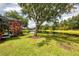 Lush backyard with mature tree and view of lake from patio at 6610 Rosy Barb Ct, Lakewood Ranch, FL 34202