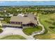 Aerial view of a golf course and neighborhood with a clubhouse, palm trees, and manicured landscaping at 7634 Windy Hill Cv, Bradenton, FL 34202