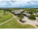 Aerial view of a golf course and neighborhood with a clubhouse, palm trees, a lake, and manicured lawns at 7634 Windy Hill Cv, Bradenton, FL 34202