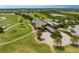 Aerial view of a golf course and neighborhood with a clubhouse, palm trees, and manicured lawns at 7634 Windy Hill Cv, Bradenton, FL 34202
