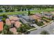 Overhead shot of an elegant home with a tile roof, lush landscaping, and a pond nearby at 7634 Windy Hill Cv, Bradenton, FL 34202