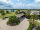 Aerial view of a golf course and neighborhood with a clubhouse, palm trees, a lake, and manicured landscaping at 7634 Windy Hill Cv, Bradenton, FL 34202