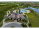 Aerial view of the community's clubhouse, pool, and landscaping near a lake at 7634 Windy Hill Cv, Bradenton, FL 34202