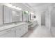 Bright bathroom featuring double vanity sinks, white cabinets, a walk-in shower, and modern fixtures at 7634 Windy Hill Cv, Bradenton, FL 34202