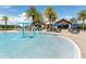 Resort-style community pool with splash fountain and lounge area surrounded by lush palm trees at 7634 Windy Hill Cv, Bradenton, FL 34202