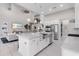Kitchen island with stainless steel appliances, white cabinetry, and view of living area with staircase at 7634 Windy Hill Cv, Bradenton, FL 34202