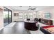 Well lit living room with gray wood flooring, ceiling fan, leather couch and chairs and large windows at 7634 Windy Hill Cv, Bradenton, FL 34202