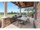 Outdoor kitchen featuring built-in grill, stone accents, a wood ceiling, and views of the lush landscape at 7634 Windy Hill Cv, Bradenton, FL 34202