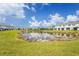 Exterior view of the property featuring a pond, manicured landscaping, and blue skies at 8705 Winter Breeze Way, Sarasota, FL 34241