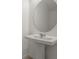 Elegant pedestal sink with an oval mirror in a minimalist powder room at 8705 Winter Breeze Way, Sarasota, FL 34241