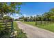 Long driveway leading to a charming white home, surrounded by a wooden fence and mature trees at 1408 99Th Nw St, Bradenton, FL 34209