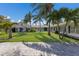 Expansive front yard featuring a meticulously maintained lawn and a charming white home framed by swaying palm trees at 1408 99Th Nw St, Bradenton, FL 34209