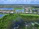 Aerial view showcasing a home with a screened pool, lush greenery, and serene waterfront views at 16917 Clearlake Ave, Lakewood Ranch, FL 34202