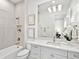 Bright bathroom featuring a shower-tub combo, white cabinets, neutral tile, and elegant decorative touches at 16917 Clearlake Ave, Lakewood Ranch, FL 34202