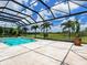 Screened pool area featuring travertine tile, a waterfall feature, and unobstructed views of green space at 16917 Clearlake Ave, Lakewood Ranch, FL 34202