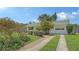 Home featuring a long driveway, garage, and landscaped front yard with mature trees at 2088 Grove St, Sarasota, FL 34239