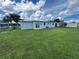 Spacious backyard featuring a grassy lawn and light blue house with modern windows and a sliding glass door at 22214 Felton Ave, Port Charlotte, FL 33952