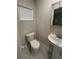 A half bathroom featuring a pedestal sink, toilet, and window with white blinds at 22214 Felton Ave, Port Charlotte, FL 33952