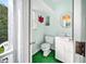 Small bathroom featuring a toilet, sink, wall mirror, and a window with artificial grass flooring at 22378 Peachland Blvd, Port Charlotte, FL 33954