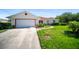 Well-maintained home featuring an attached garage, mature landscaping, and a concrete driveway at 22378 Peachland Blvd, Port Charlotte, FL 33954
