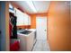 Functional laundry room with orange accent wall, washer, dryer, cabinets, and tile flooring at 22378 Peachland Blvd, Port Charlotte, FL 33954
