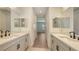Bathroom view featuring dual sinks with modern fixtures and a hallway leading to a sunlit room at 248 Altamura Cir, Nokomis, FL 34275