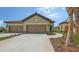Beige two-car garage with paved driveway and stone accents in a Florida community at 248 Altamura Cir, Nokomis, FL 34275