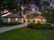 Charming home with red tile roof, arched windows, and lush landscaping under a picturesque sky at twilight at 2504 Tanglewood Dr, Sarasota, FL 34239
