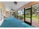 Relaxing screened porch with blue carpet flooring, fan, and beautiful views of the landscaped backyard at 2559 Wood Oak Dr, Sarasota, FL 34232