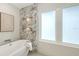 Modern bathroom featuring a soaking tub, marble wall accents, and natural light from the large window at 2590 Floyd St, Sarasota, FL 34239